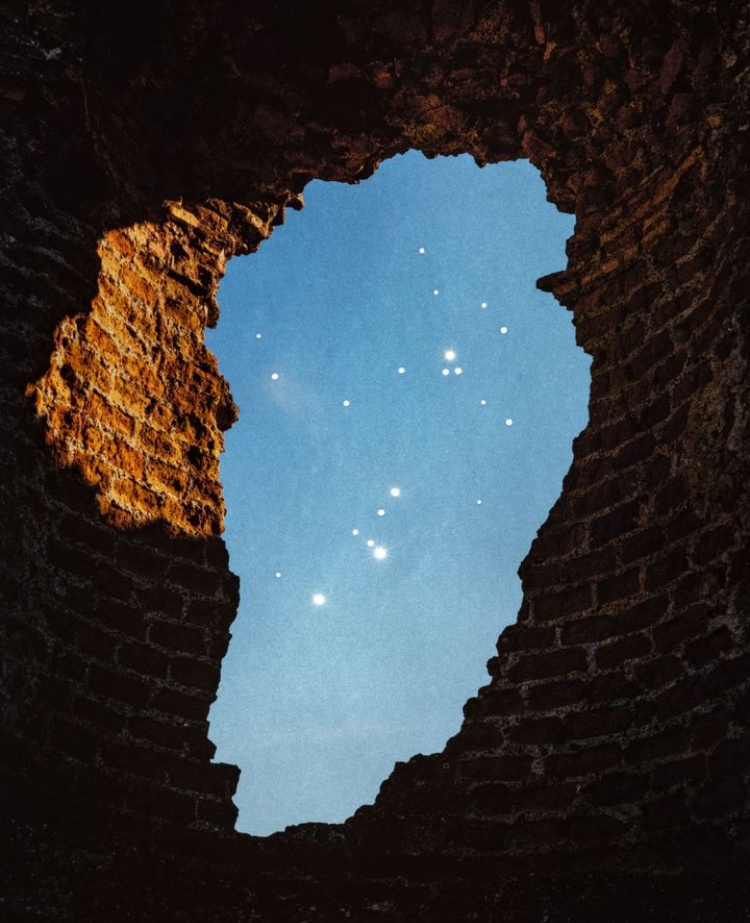 A ruin opening framing stars in a blue sky